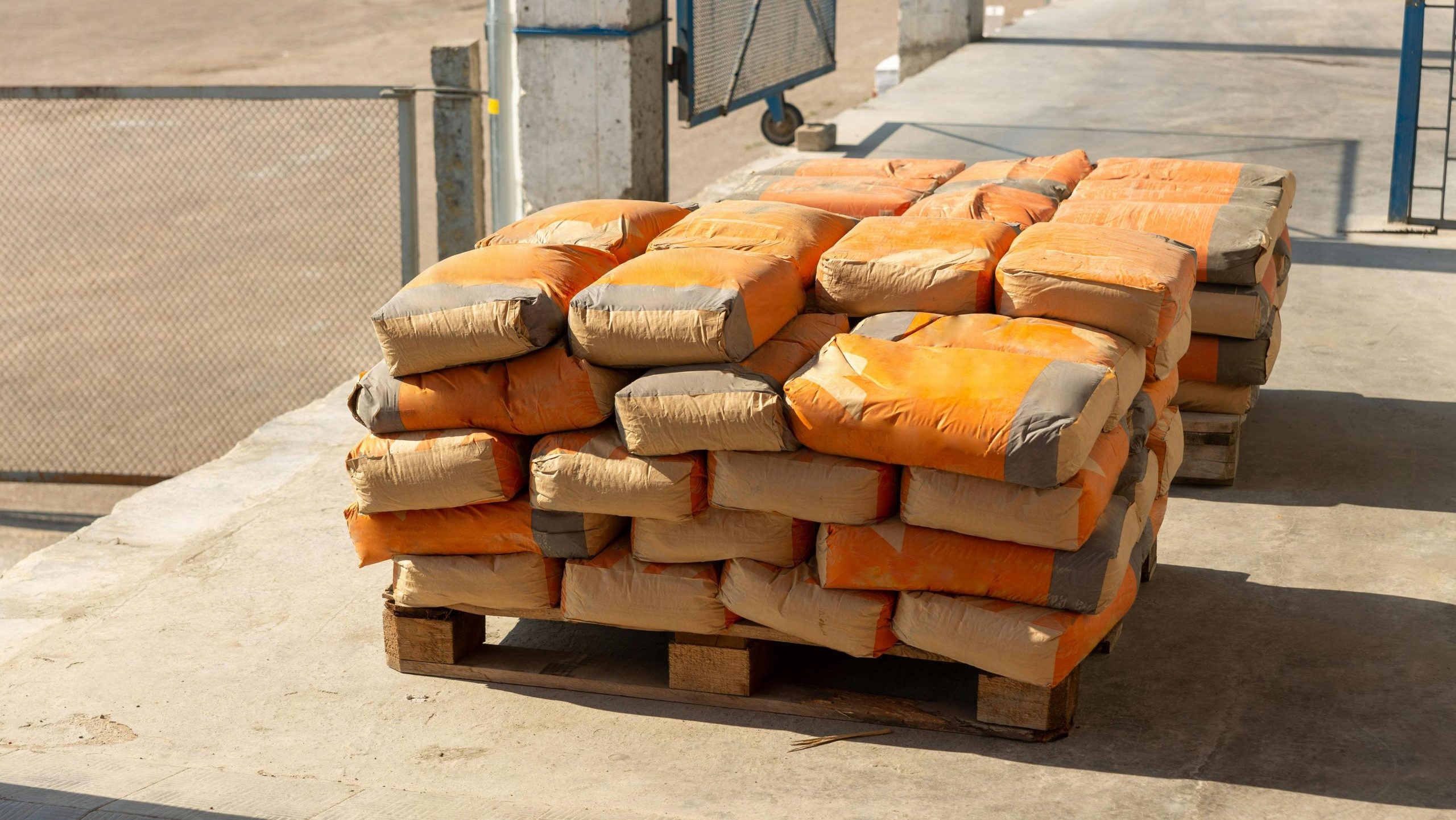 Pile of orange cement bags on a wooden pallet in an industrial setting.